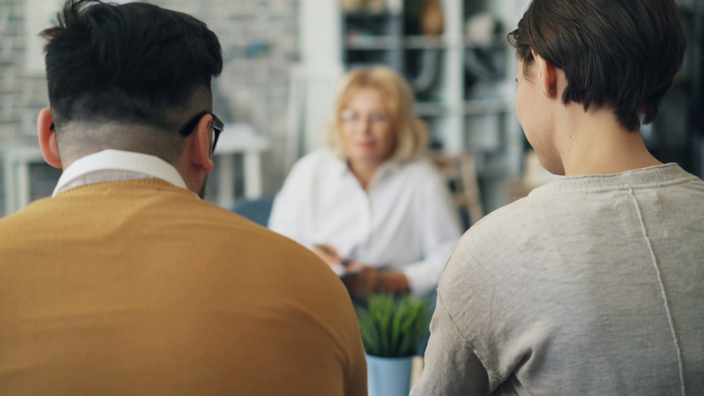 Pareja en consulta con un terapeuta en una oficina.