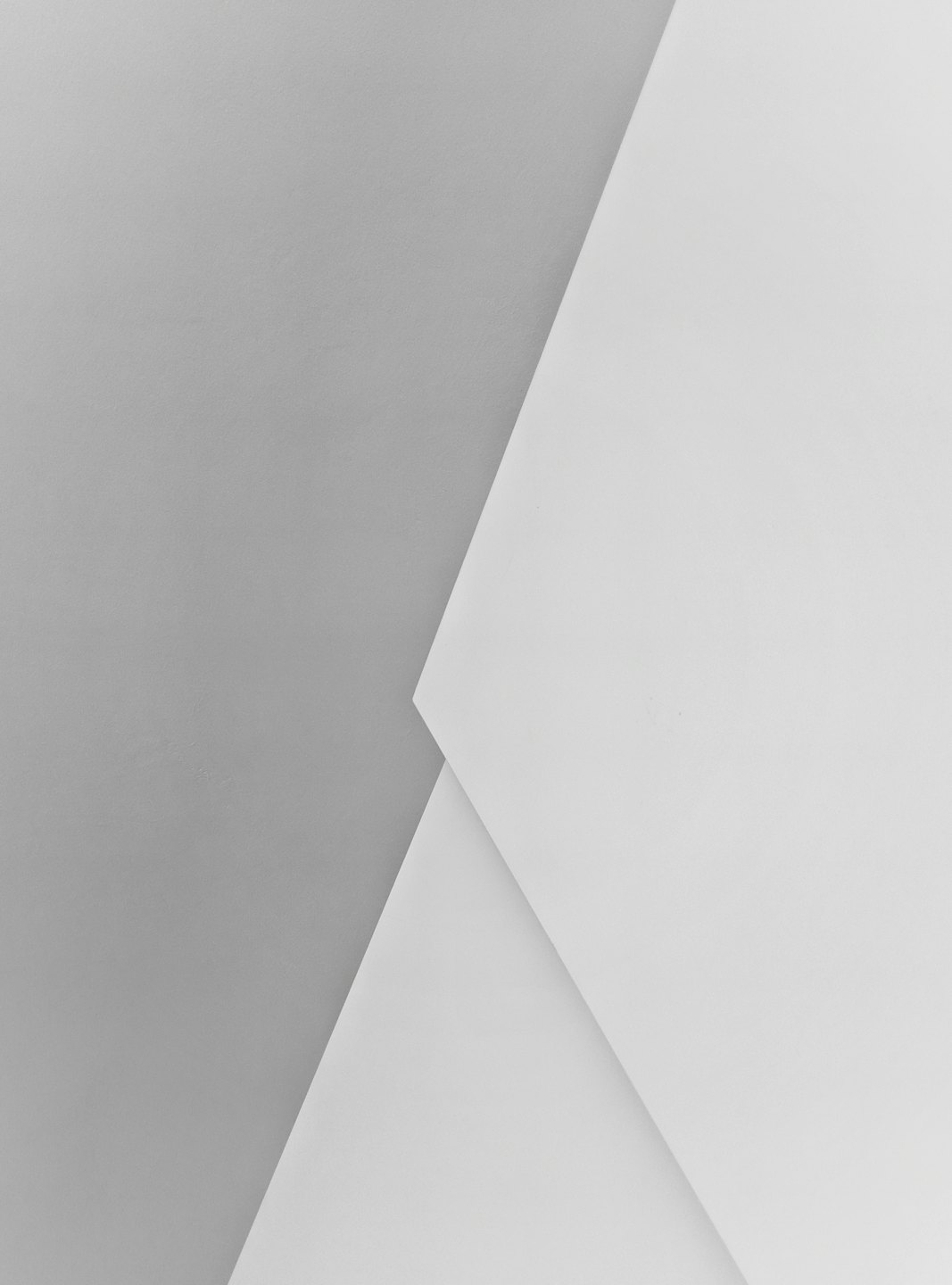 Formas geométricas formadas por planos que se cruzan en gris claro y blanco.